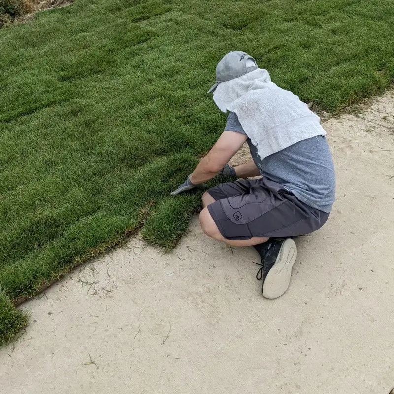 Worker trimming and fitting sod during a professional installation
